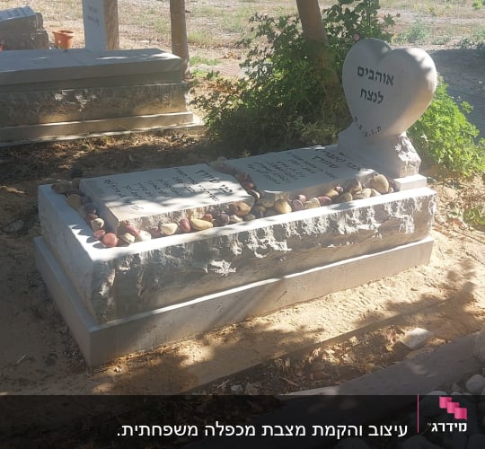 קבר עם מצבה בצורת לב ואבנים מסביב